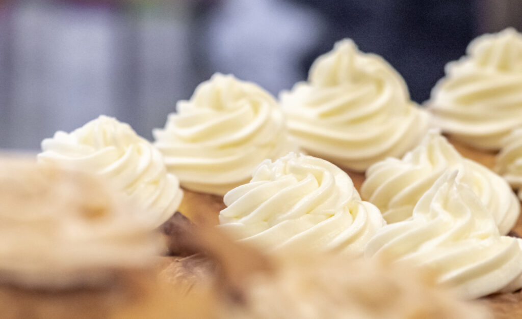 Close up photo of a tray of cinnamon buns with cream cheese icing on top.