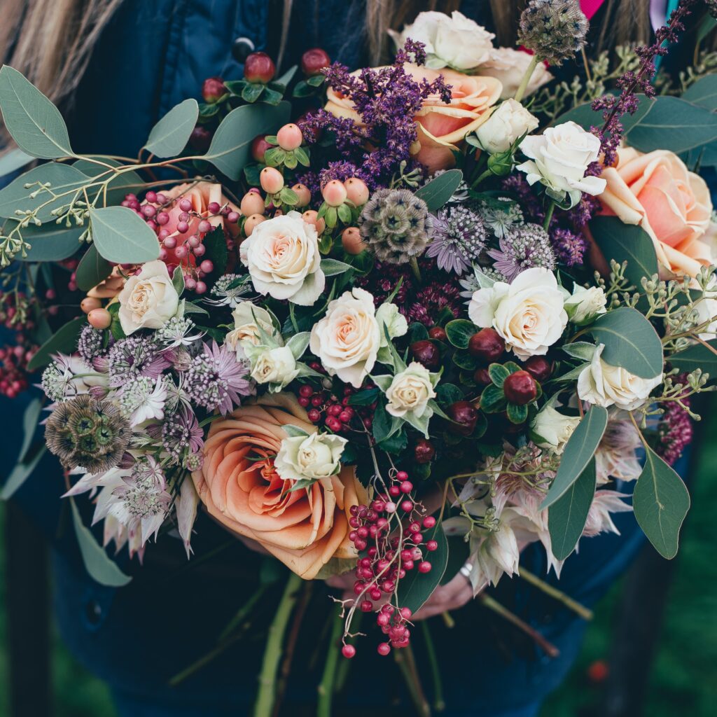 Large bouquet of flowers including white and orange roses.